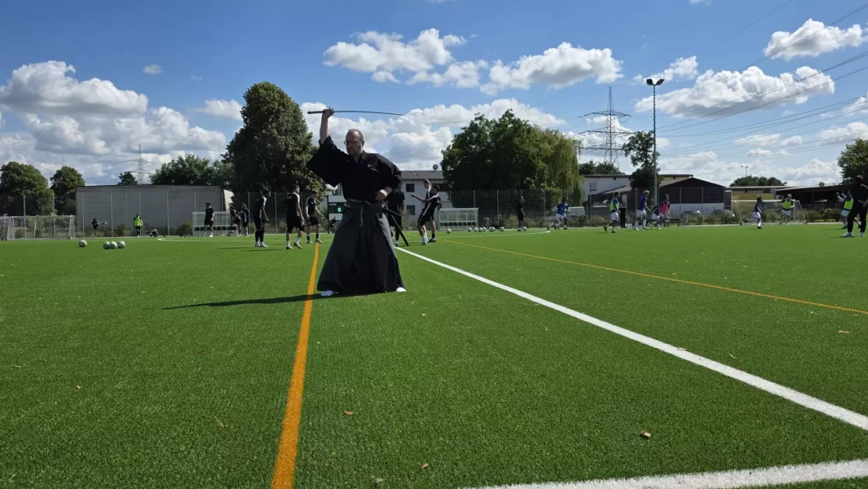 a man in black robe holding a sword on a football field