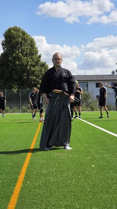 a man standing on a field with a sword and a group of people