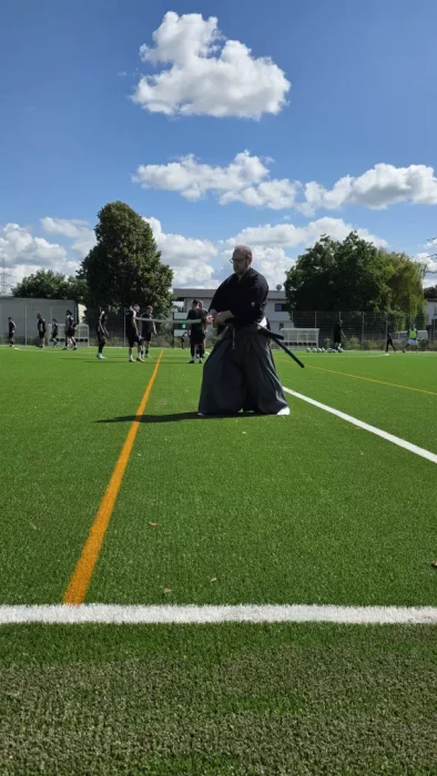 a man in a black robe on a football field with a sword