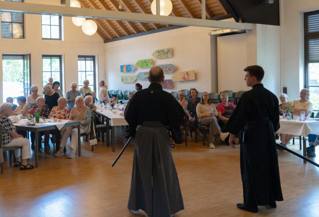 a man in a black robe holding a sword in front of a group of people