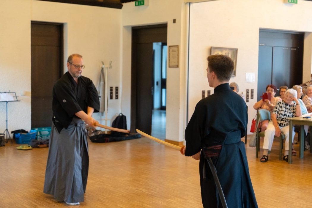 a group of people in black robes holding wooden sticks